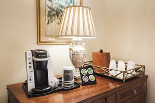 Una estación de café con una cafetera Keurig, una jarra y una bandeja de cápsulas de café.