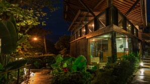 A modern building with a wooden roof and glass windows, surrounded by lush greenery.