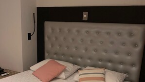 A neatly made bed with a tufted headboard, white bedding, and several pillows. - Plaza Spania (Rio de Janeiro)