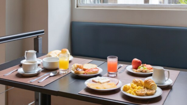 A breakfast table with various dishes and drinks, a window with a view of the street and a building with a sign. - Plaza Spania (Rio de Janeiro)