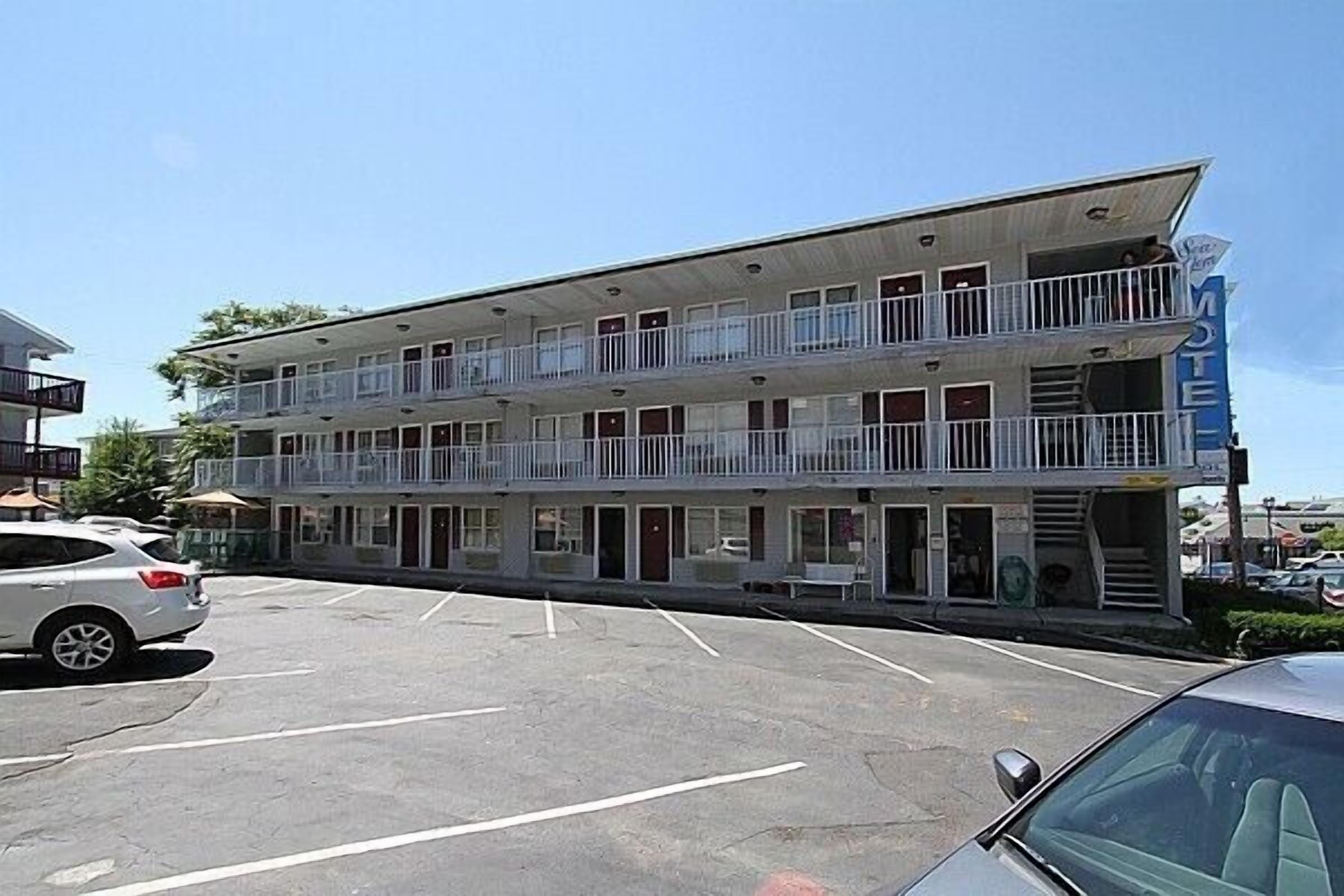 A motel with a two-story structure, multiple balconies, and a parking lot.