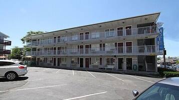 A motel with a two-story structure, multiple balconies, and a parking lot.