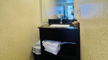 Un baño pequeño con tocador negro, espejo y lavamanos blanco.