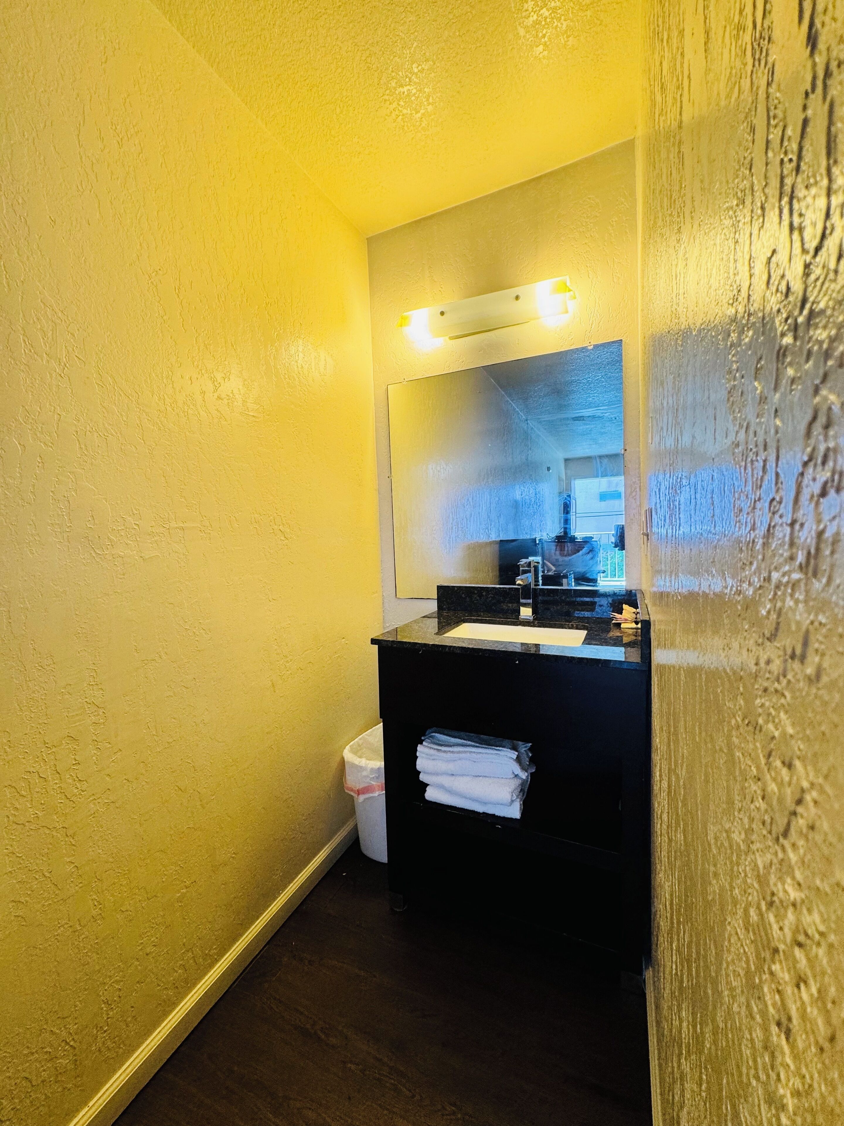 A small bathroom with a black sink, a mirror, and a single towel hanging on the wall.