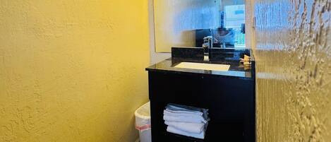 A small bathroom with a black sink, a mirror, and a single towel hanging on the wall.