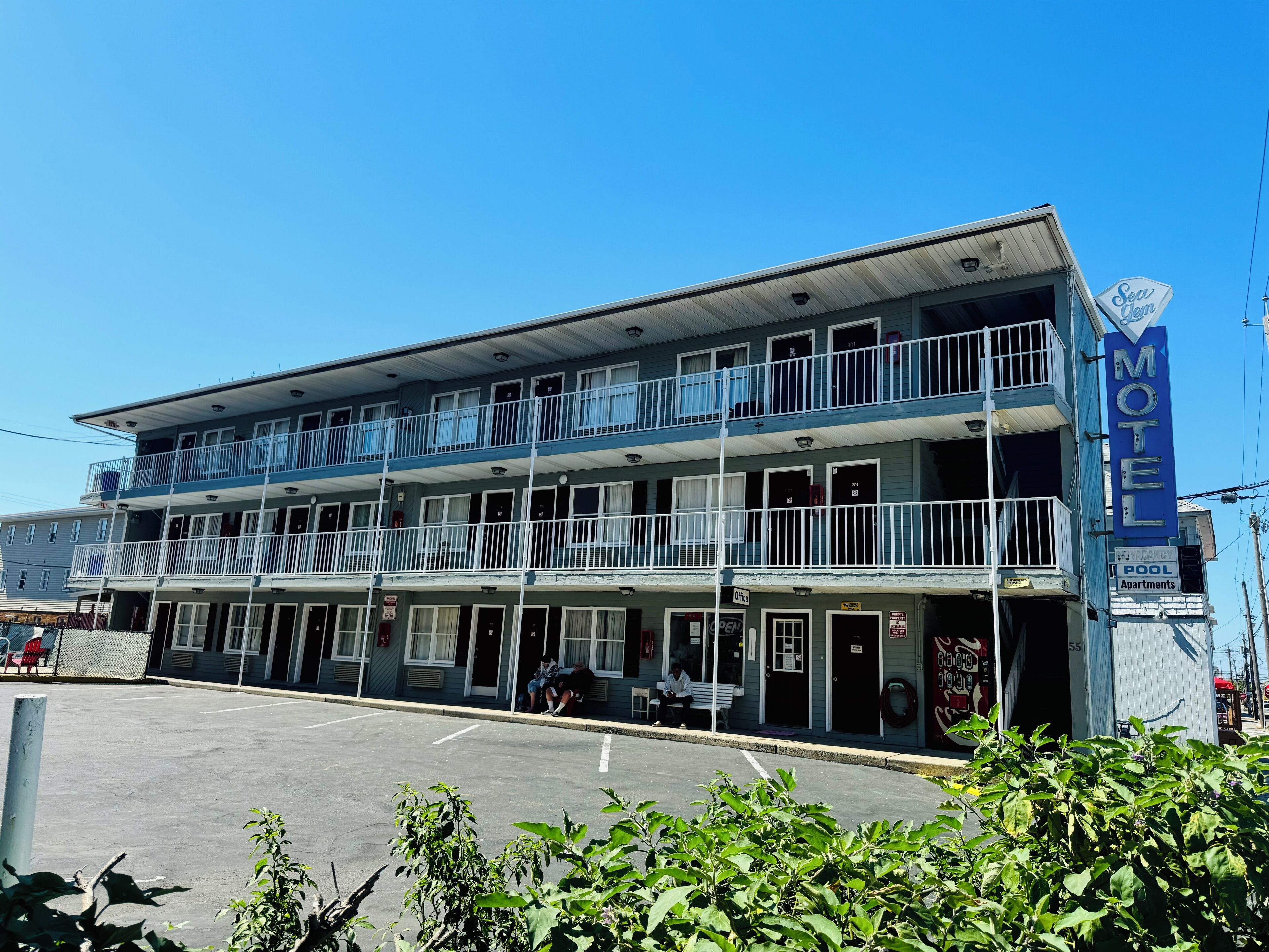 Un motel con una estructura de dos pisos, varios balcones y un letrero que indica que ofrece piscina y apartamentos.
