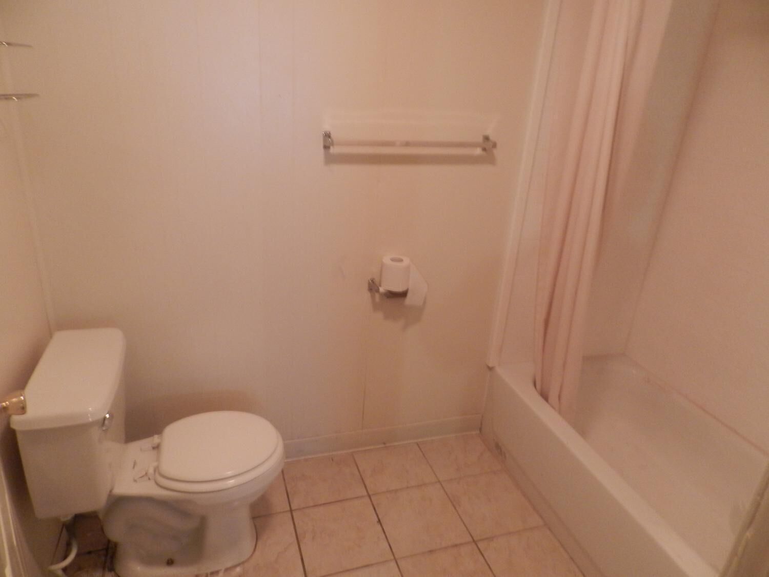 A small, clean bathroom with a toilet, a towel rack, and a shower curtain.