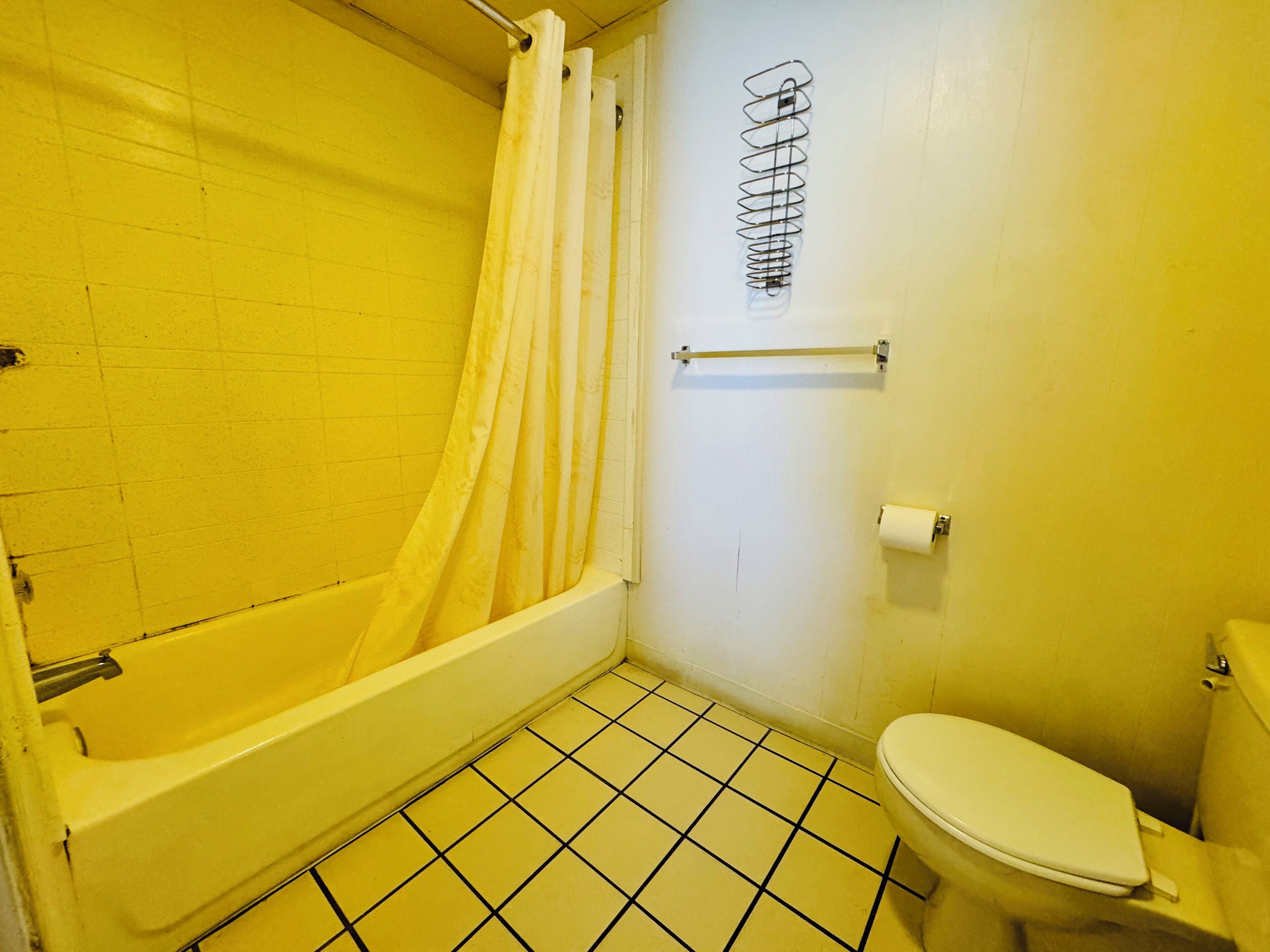 A small bathroom with a bathtub, toilet, and a shower curtain.