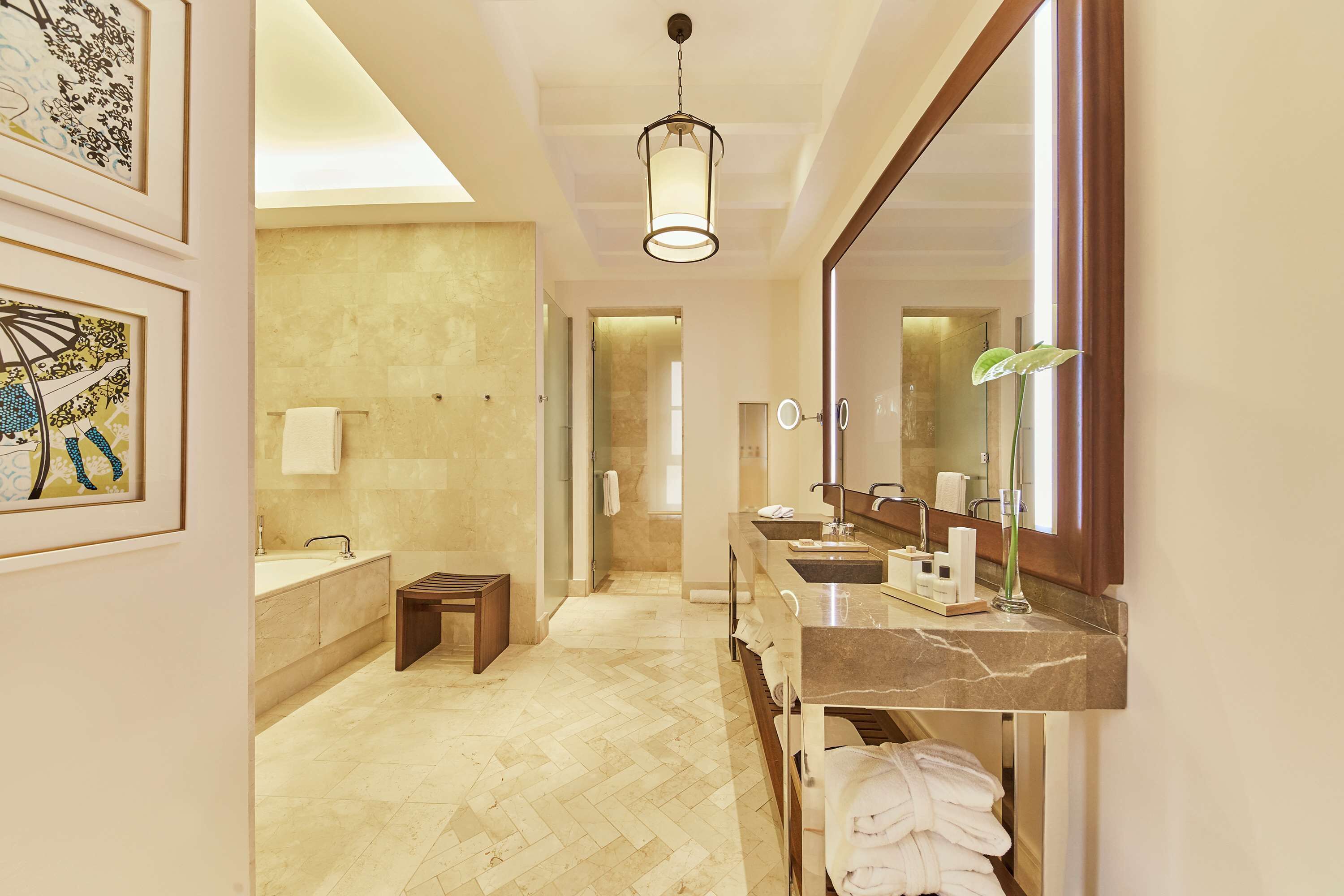 A modern bathroom with a large mirror, multiple sinks, and a wooden bench.