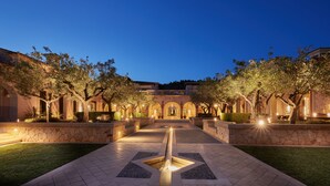 A courtyard with a central water feature, stone walls, and trees.