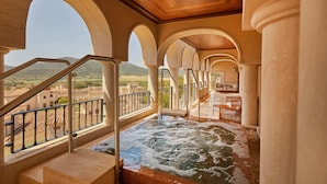 A spa area with a hot tub, wooden ceiling, and arched columns.