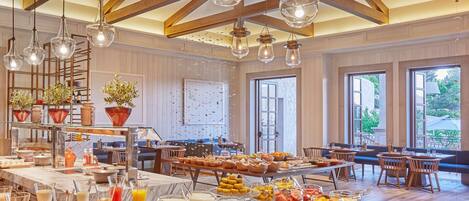 A breakfast buffet with various food items and a seating area with wooden tables and chairs.