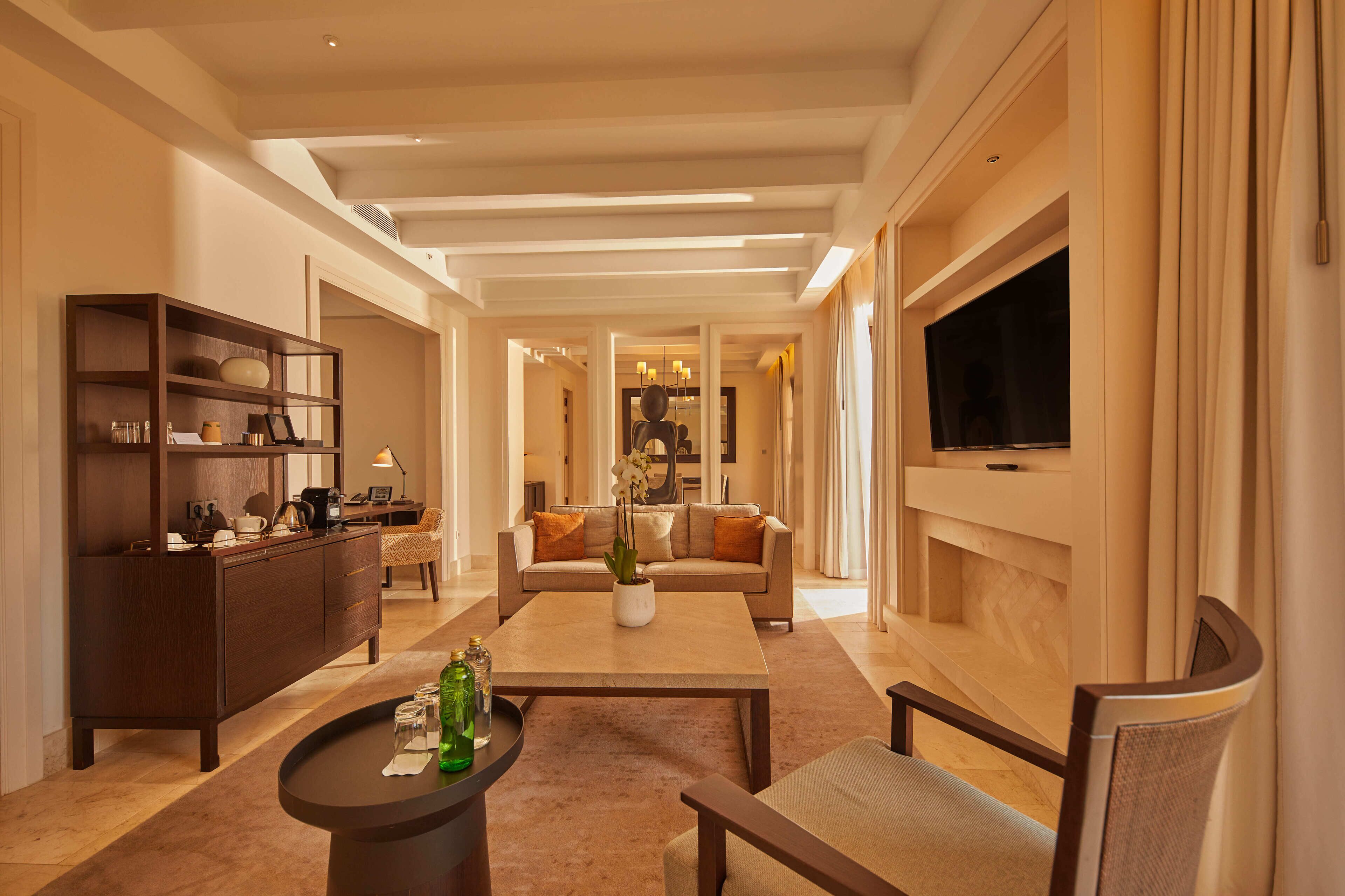 A spacious living room with a sofa, coffee table, and a TV mounted on the wall.
