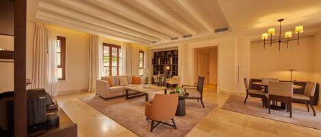 A spacious living area with a sofa, coffee table, and dining table set.