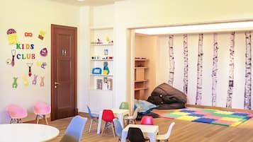 Children can play and learn in this vibrant playroom, featuring colorful chairs, tables, and a soft foam mat.