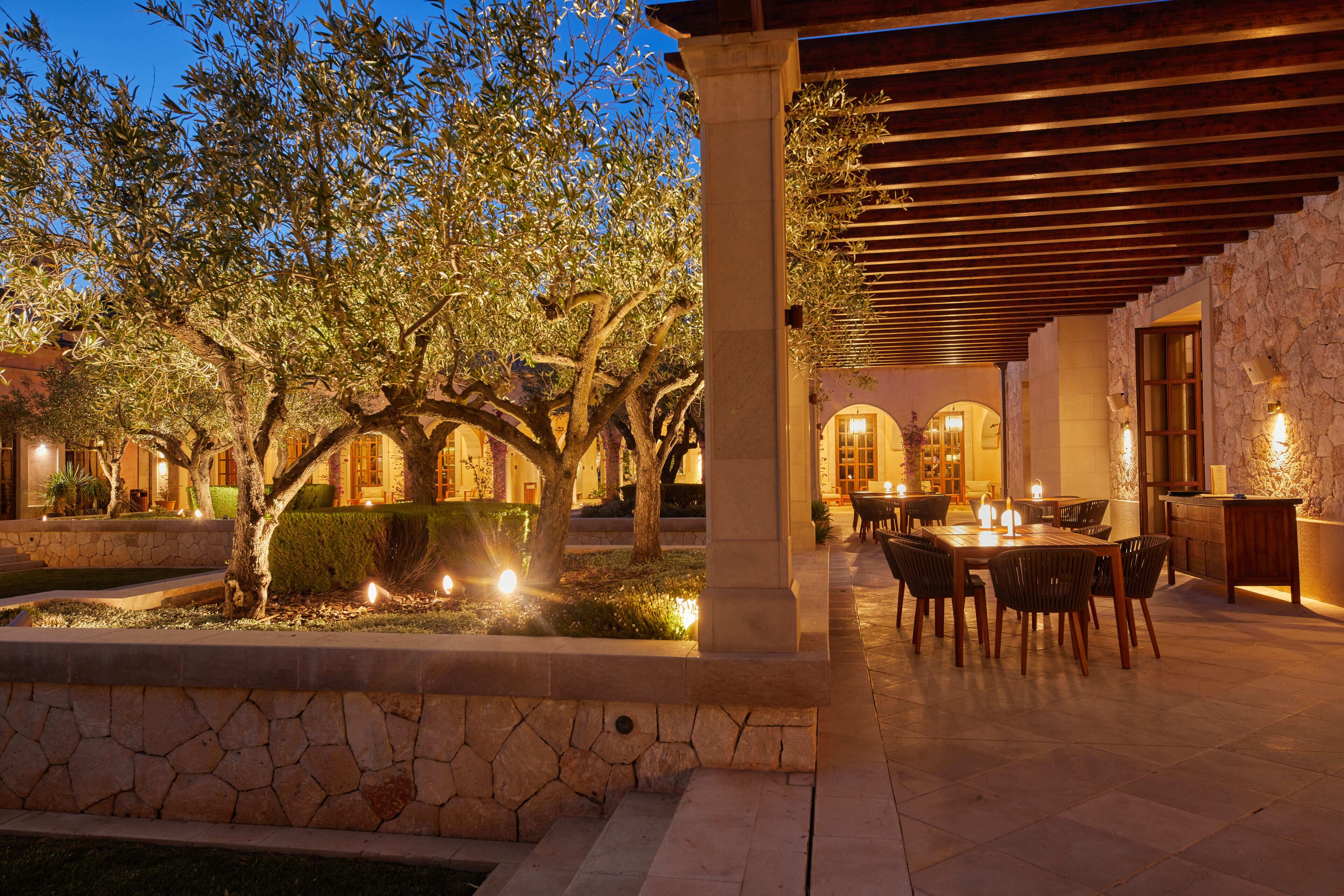 Un patio exterior con suelo de piedra, una pérgola y una mesa de comedor con sillas.