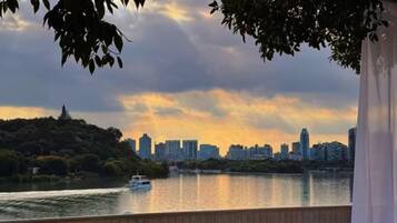 A river with a boat, a city skyline in the background, and a wooden deck.