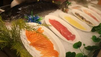 Variedad de mariscos frescos sobre hielo, incluyendo salmón y otros pescados, con adornos de follaje.