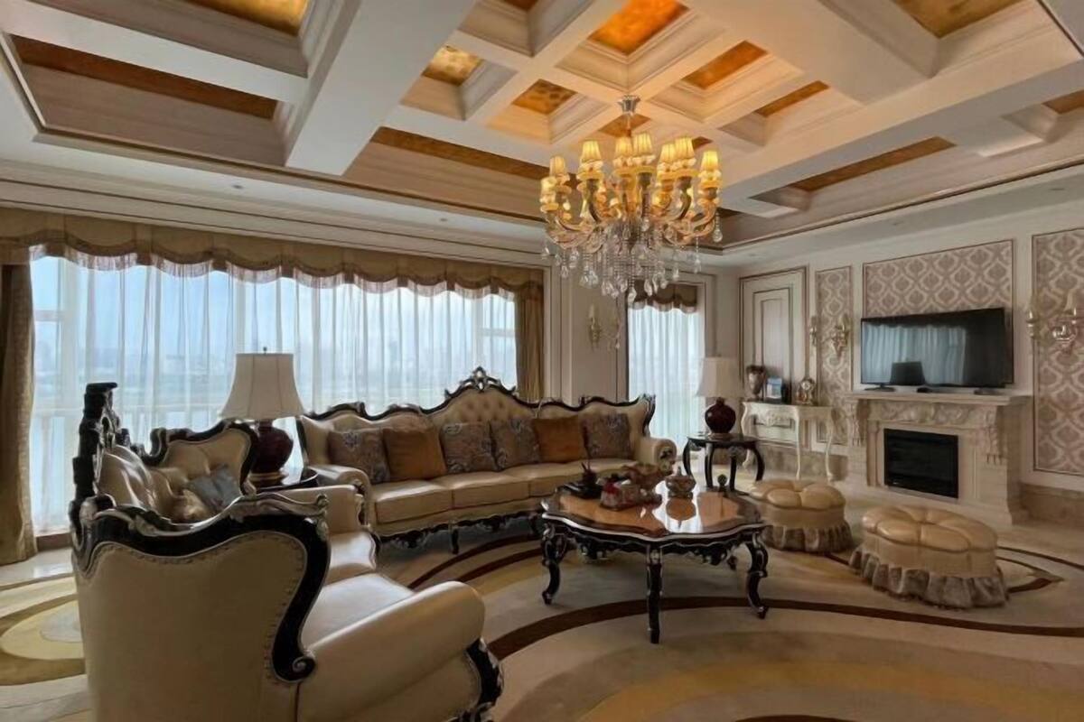Ein luxuriöses Wohnzimmer im klassischen Stil mit einer großen Couch, einem Couchtisch und einem Kamin.