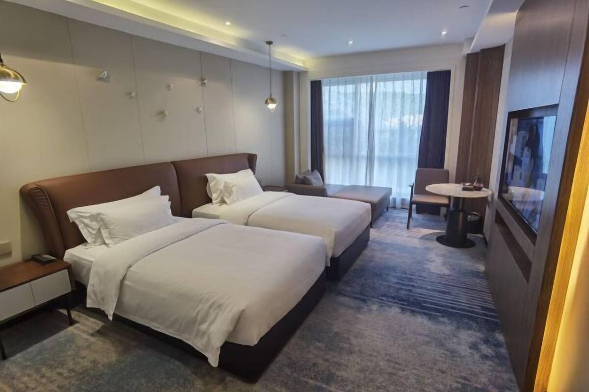 Ein Hotelzimmer mit zwei Betten, einer Sitzecke, einem kleinen Tisch und einem Fernseher.