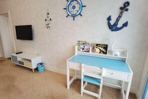 Kinderzimmer mit Schreibtisch, Fernseher und Meeresdekorationen.