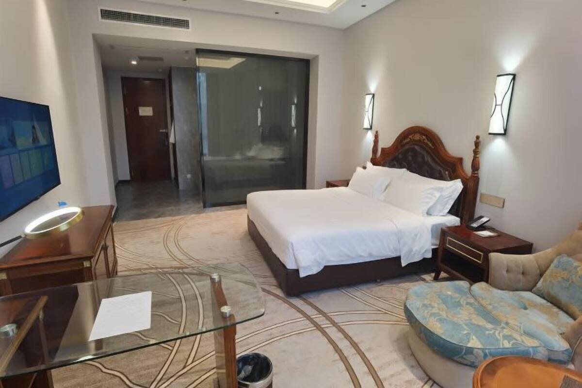 Ein Hotelzimmer mit einem Bett, einem Glastisch, einer Couch und einem Fernseher.