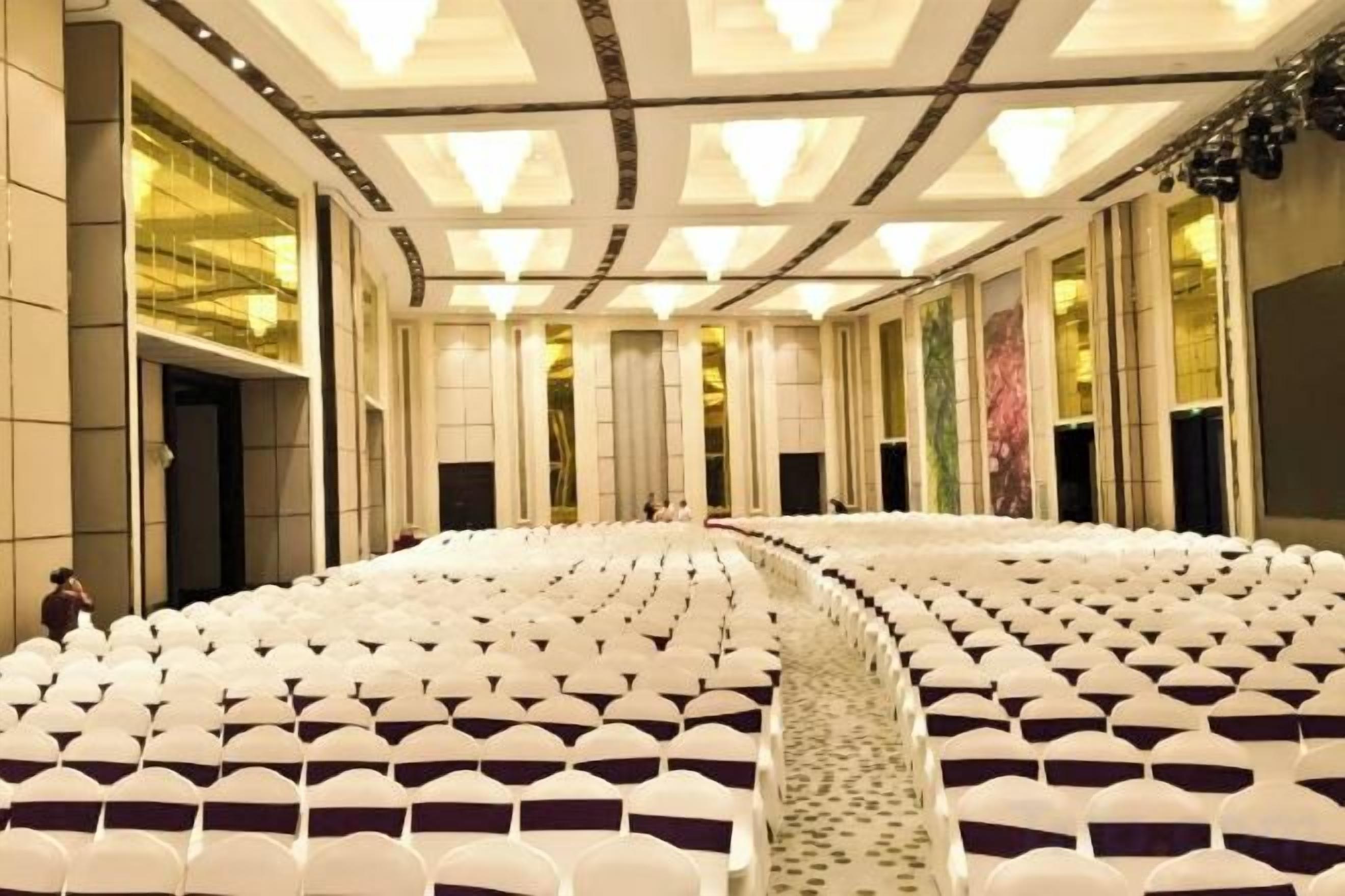 A large, circular auditorium with rows of white chairs and a central aisle.