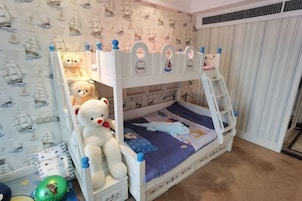 Una cama litera con escalera, un oso de peluche y un papel tapiz con motivos náuticos.
