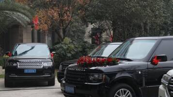 Two black SUVs parked in a driveway with a red flower arrangement on the front of one.