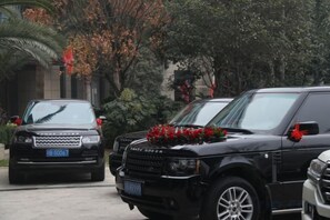 Dos SUVs negros estacionados en una entrada con un arreglo floral rojo en el frente de uno.
