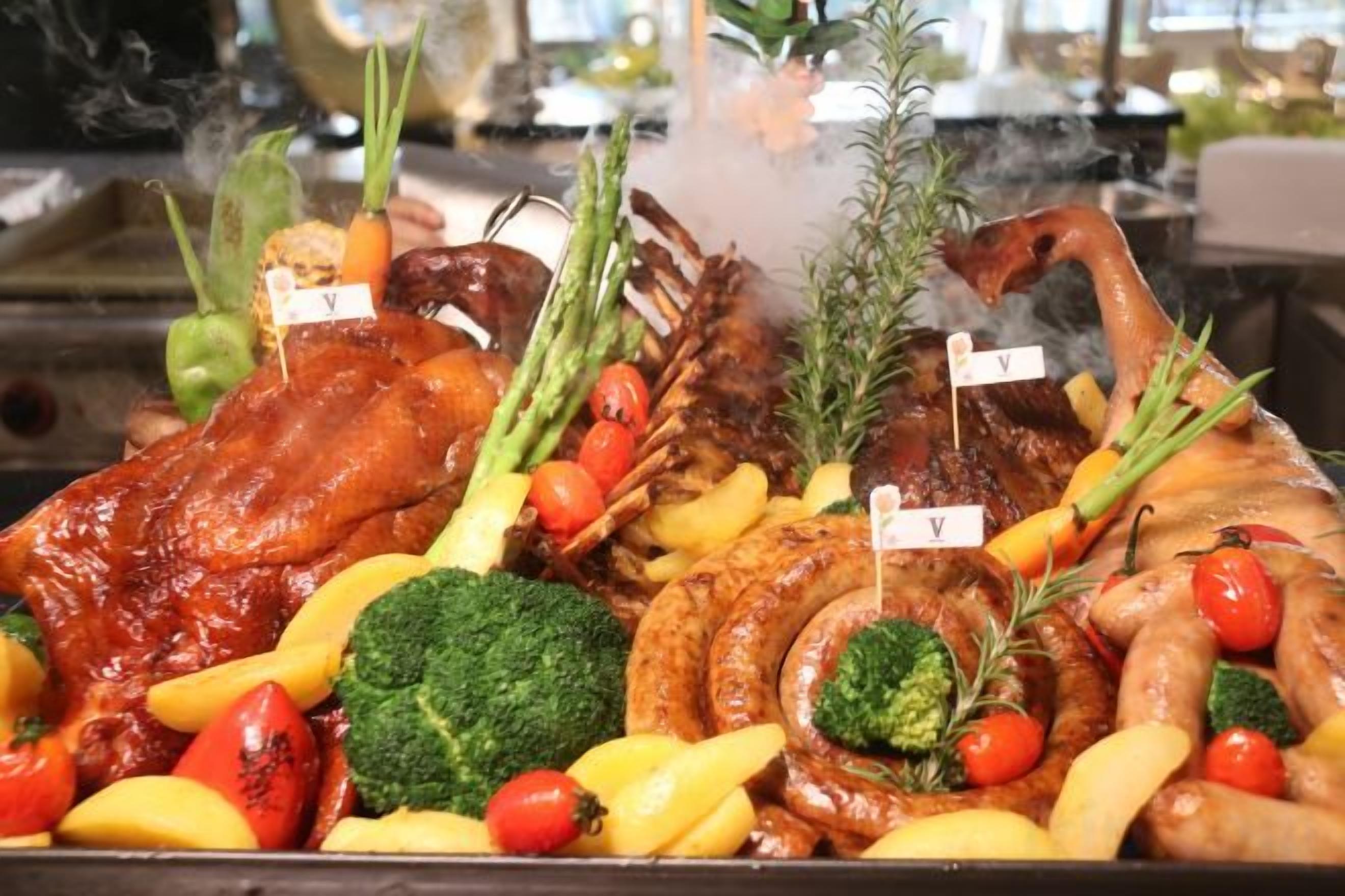 A variety of meats and vegetables on a tray, including a large piece of meat with a tag, asparagus, broccoli, and tomatoes.
