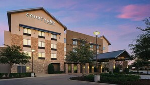 Un hôtel Courtyard by Marriott doté d’une façade en briques, de nombreuses fenêtres et d’un espace d’entrée abrité.