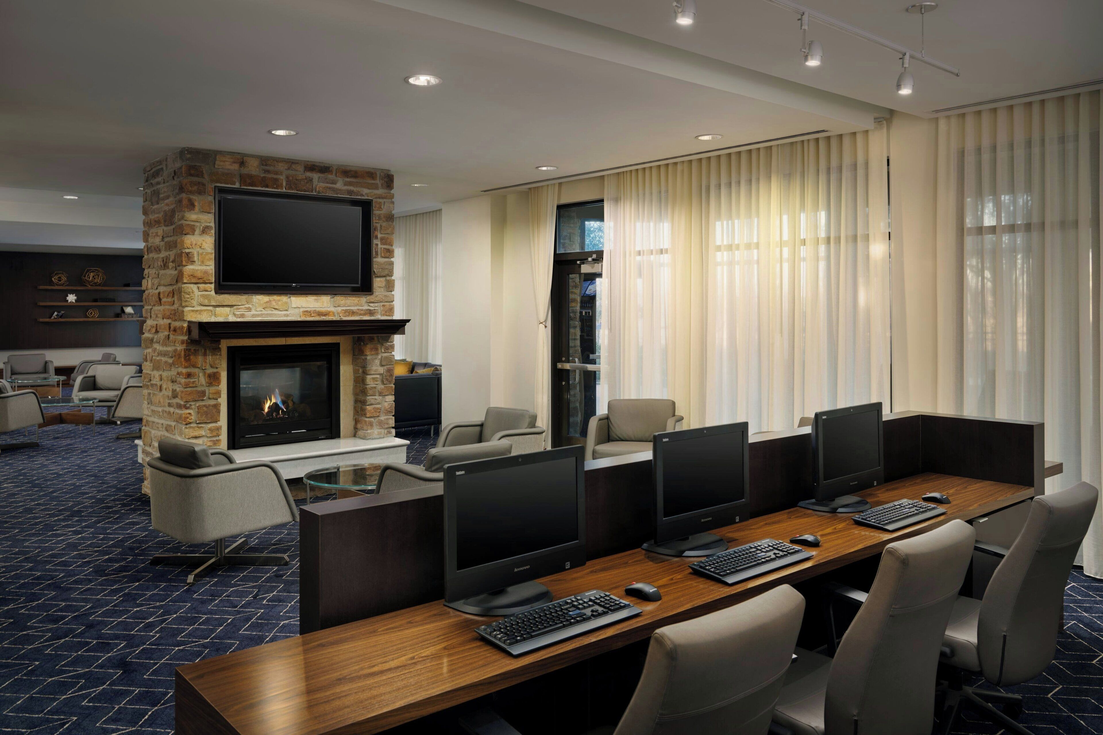 A conference room with a stone fireplace, multiple monitors, and comfortable seating.