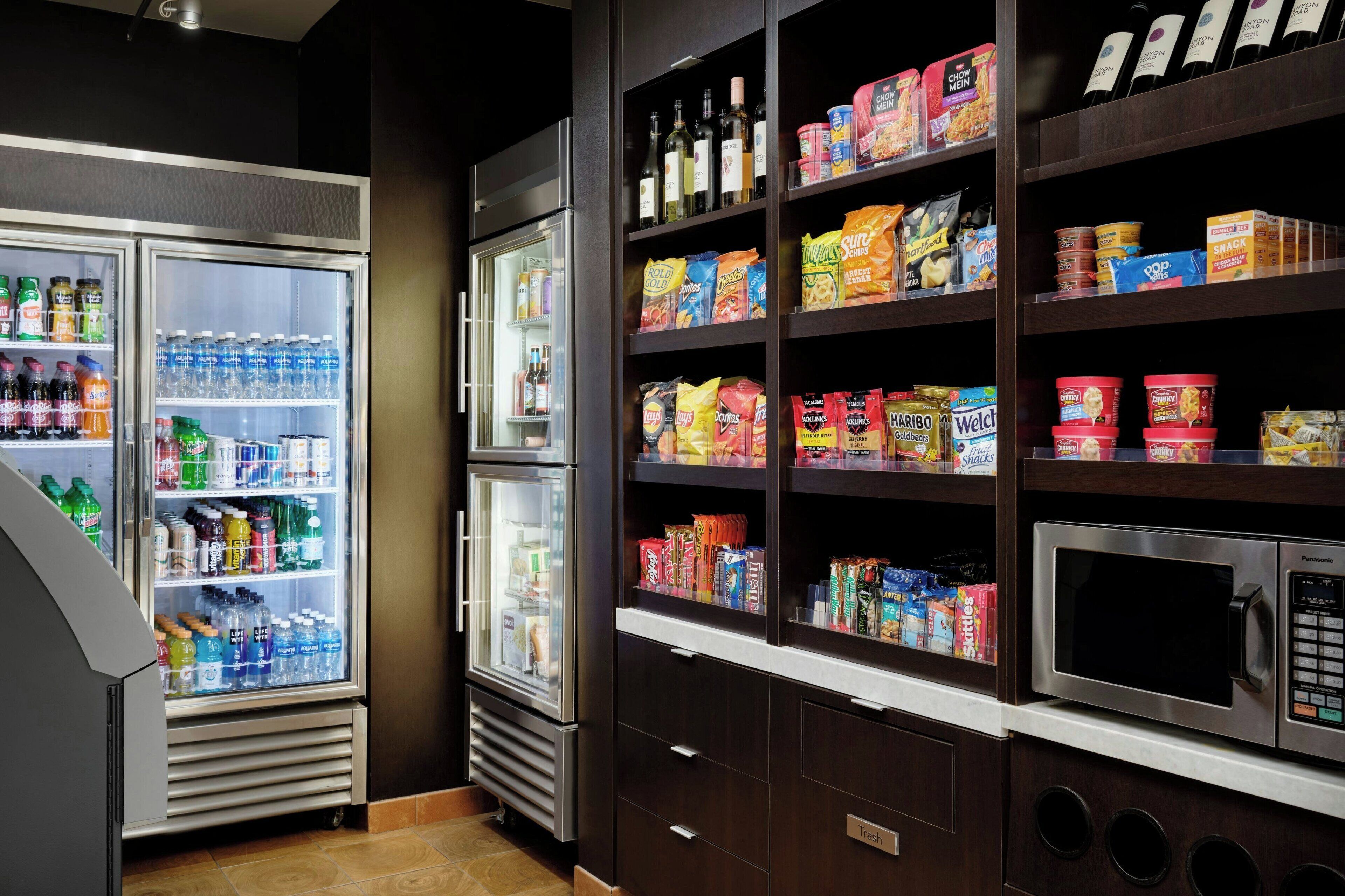 A self-service food station with refrigerated drinks, snacks, and a microwave.