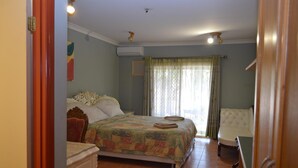 Un dormitorio con cama, una silla, una mesita de noche y una ventana con cortinas.