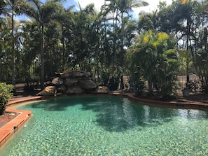 A clear pool surrounded by palm trees and a rock formation. - Heritage Resort (Nanum)