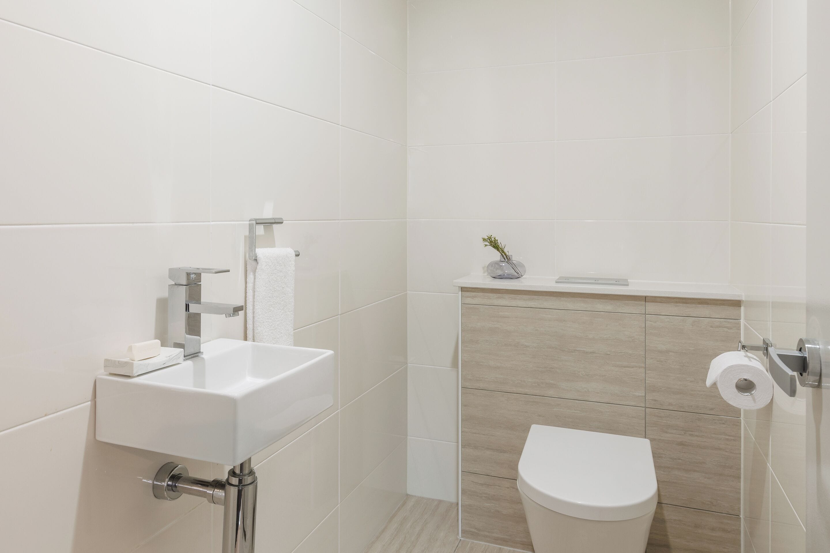 Ein modernes Badezimmer mit Waschbecken, Toilette und einer kleinen Ablage für Toilettenartikel.