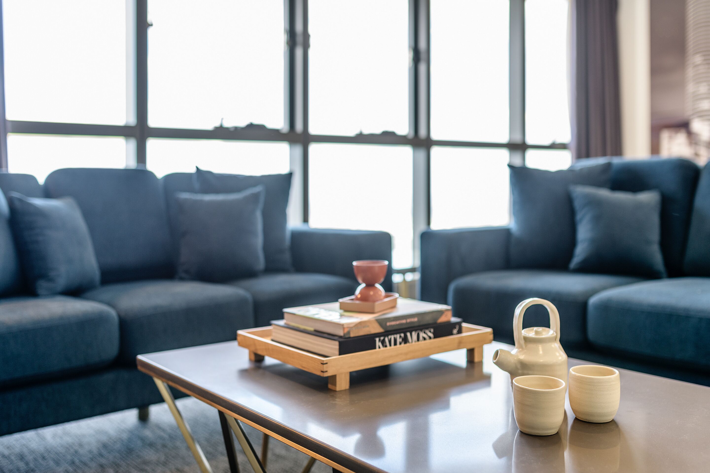A modern living room with a sofa, a coffee table, and a window with blinds.