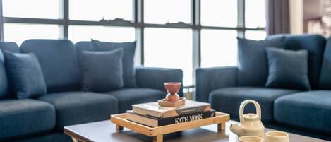 A modern living room with a sofa, a coffee table, and a window with blinds.