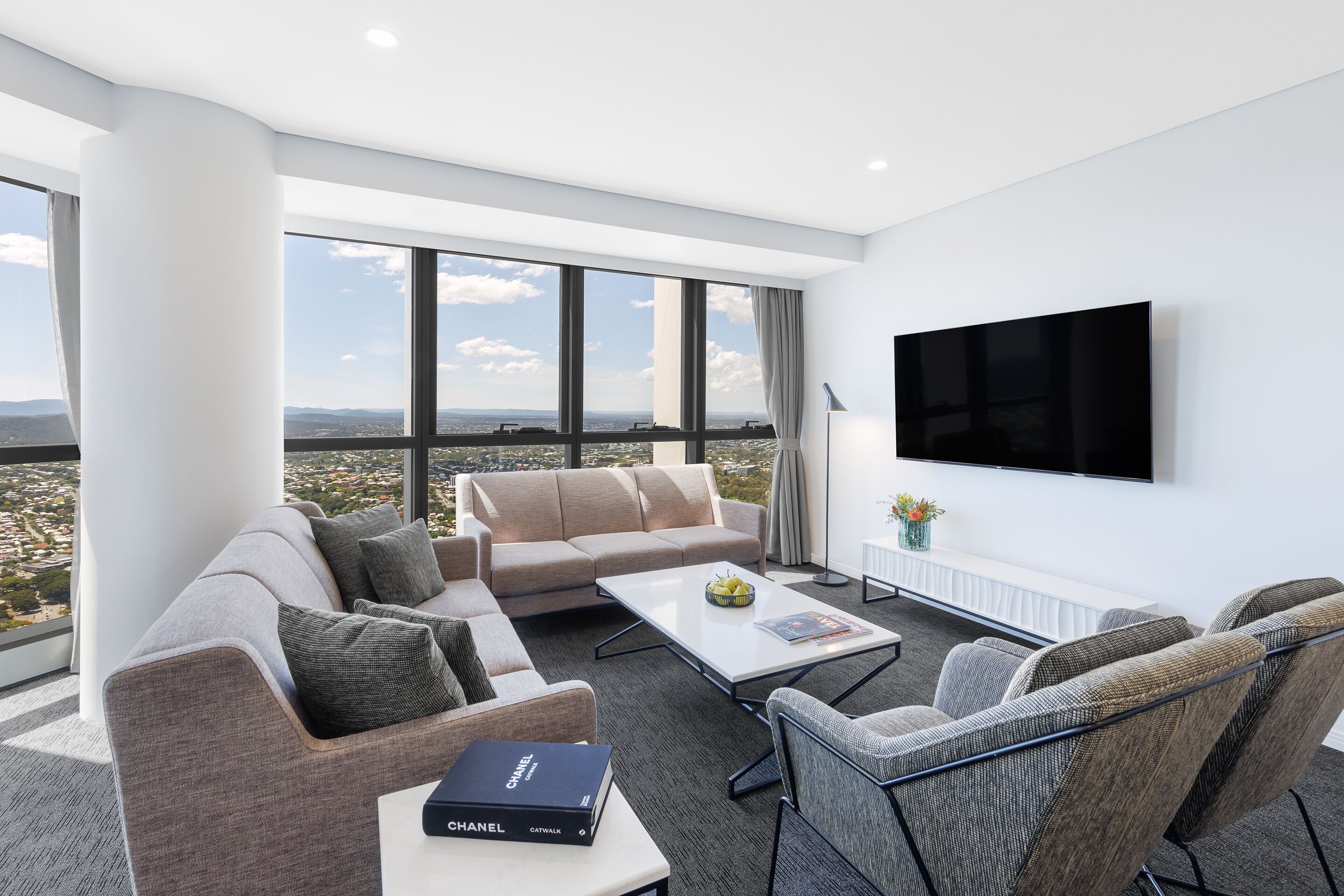A modern living room with a sofa, armchairs, a coffee table, and a flat-screen TV.