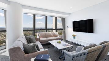 A modern living room with a sofa, armchairs, a coffee table, and a flat-screen TV.