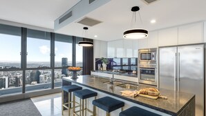 Una cocina moderna con una isla grande, electrodomésticos de acero inoxidable y vista a la ciudad.