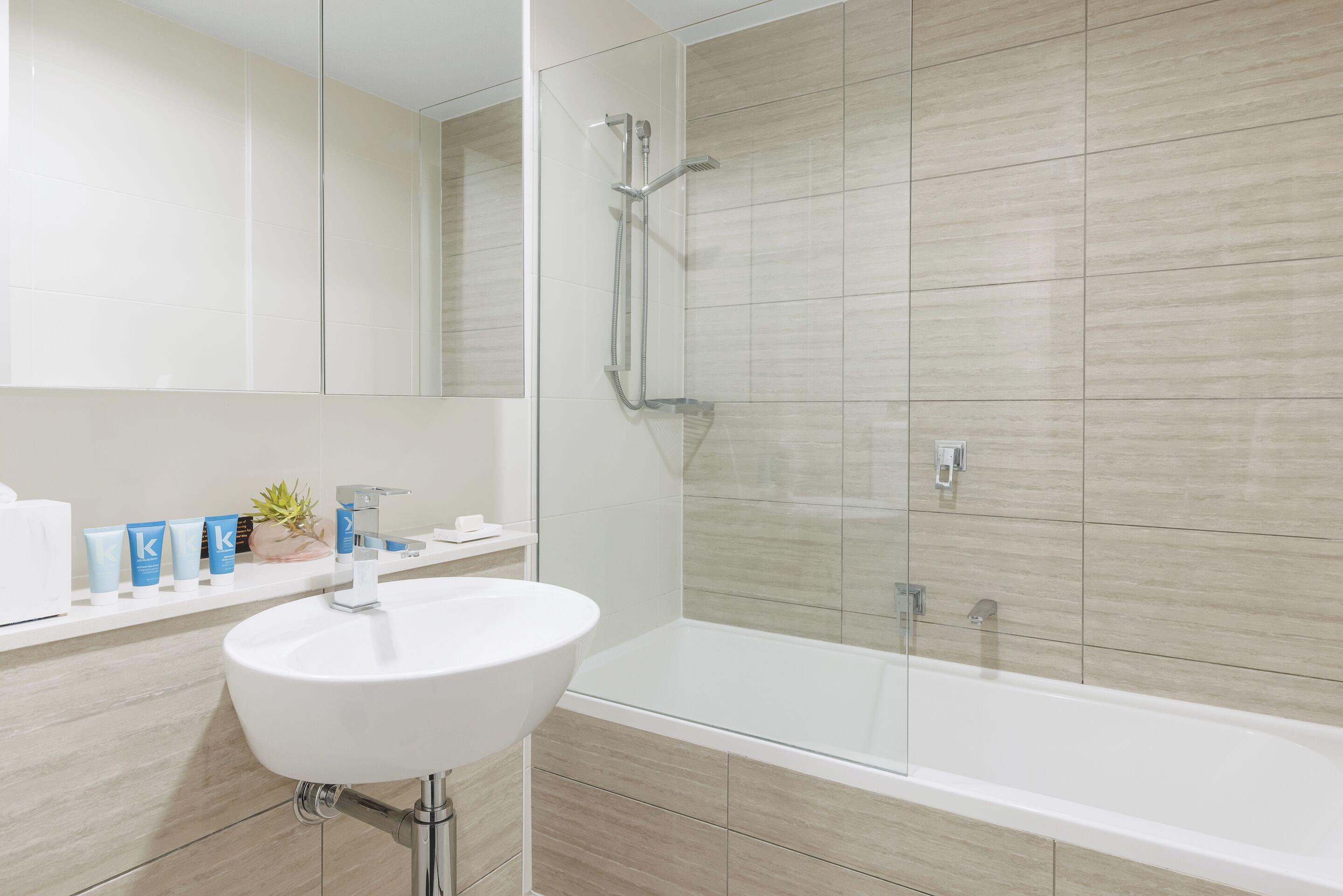 A modern bathroom with a white sink, a glass-enclosed shower, and a bathtub.