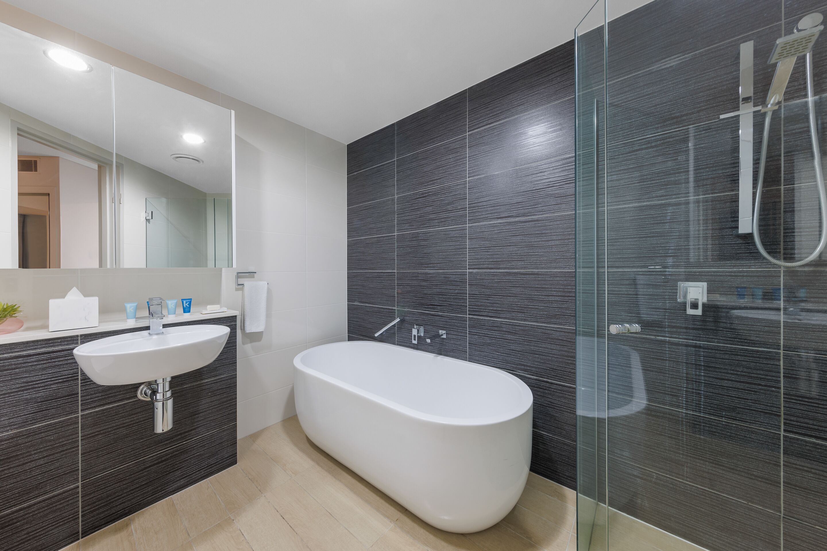 A modern bathroom with a freestanding bathtub, a glass-enclosed shower, and a white sink.