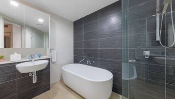 A modern bathroom with a freestanding bathtub, a glass-enclosed shower, and a white sink.