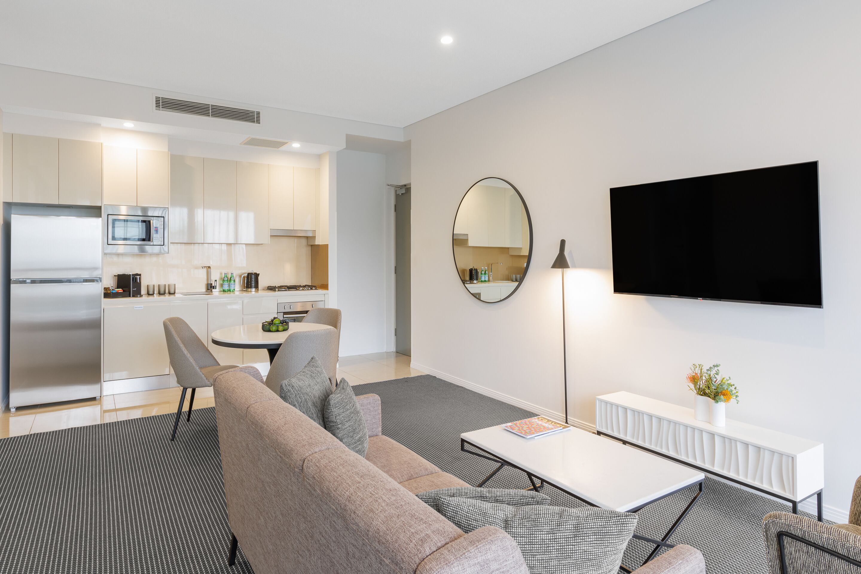 A modern living room with a sofa, coffee table, and a flat-screen TV mounted on the wall.