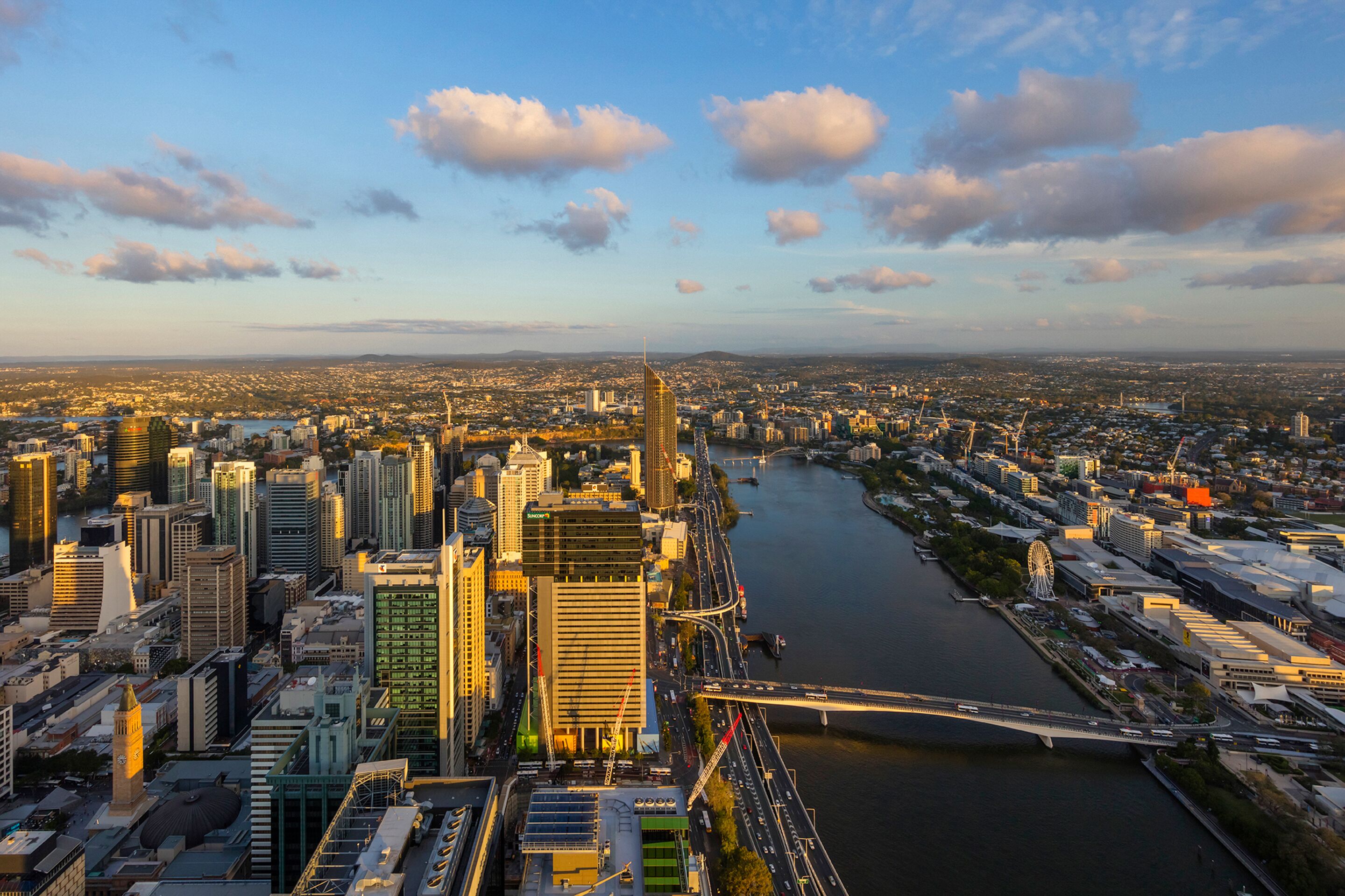 A cityscape with a river, modern buildings, and a bridge.