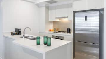 Eine moderne Küche mit einem Edelstahlkühlschrank, weißen Schränken und einer weißen Arbeitsplatte.