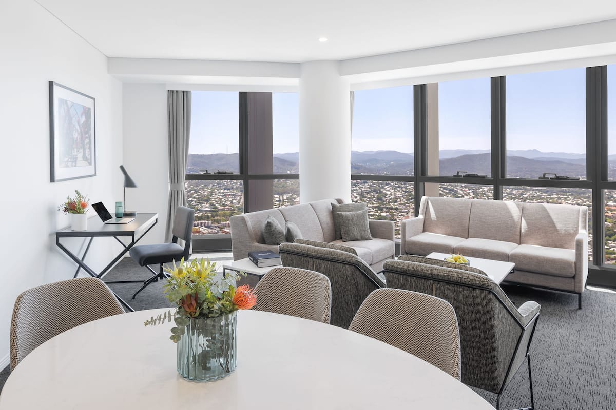 A modern living room with a city view, a dining area, and a workspace.