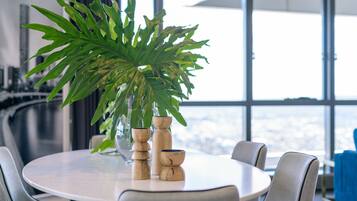 A round dining table with chairs, a large potted plant, and two wooden vases.